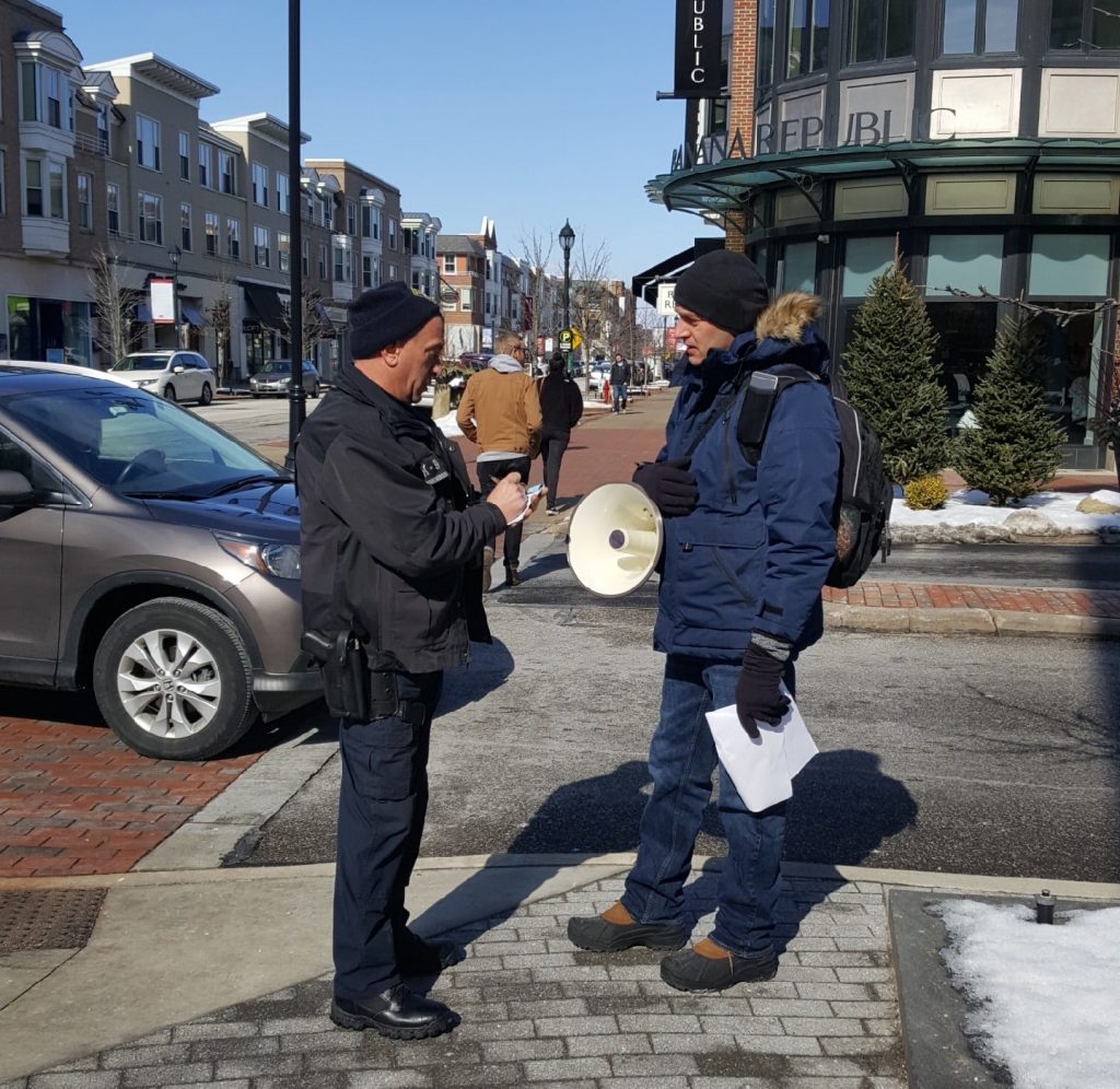 SMART Education Department Director Eli Baccus speaks to a police officer while holding hand bills and a megaphone during his time as an organizer with Local 33.